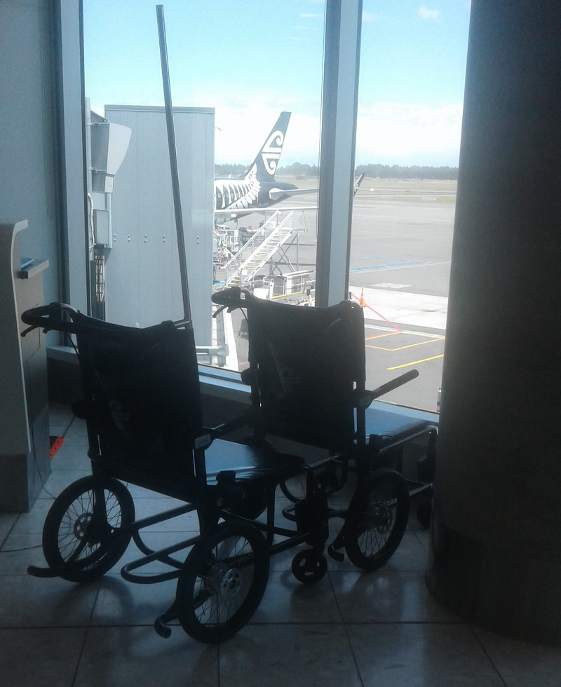 Wheelchairs at an airport with a partial view of a plane